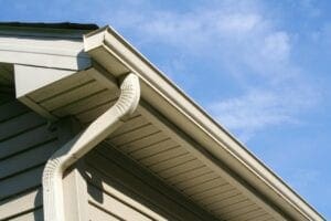 Close-up of a house gutter system under a blue sky.