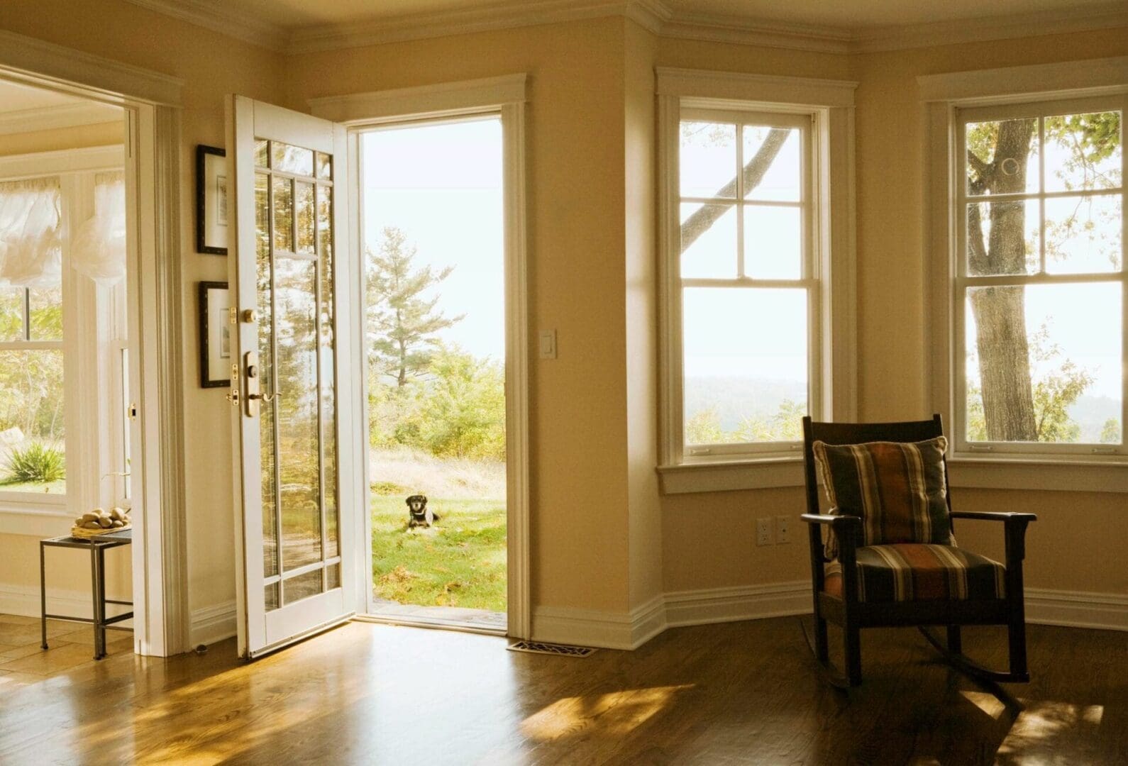 Sunlit room with open door leading to a garden and a chair by the window.